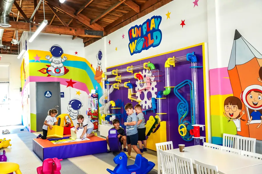 Children playing at a STEM interactive pneumatic ball run wall and soft building block area