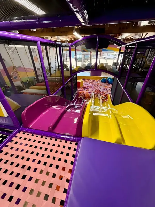 Children sliding down a custom space-themed wide slide into a colorful giant ball pit