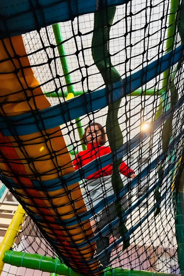 Child in rope net tunnel at Speelpunt Zwevegem indoor playground